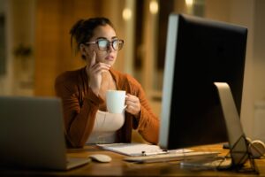 Young Pensive Woman Drinking Tea While Reading E Mail On Compute
