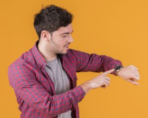 Young Man Checking Time His Wristwatch Against Orange Background Cropped